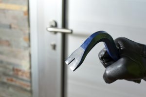 Thief with a bar of iron in the hand to open a door